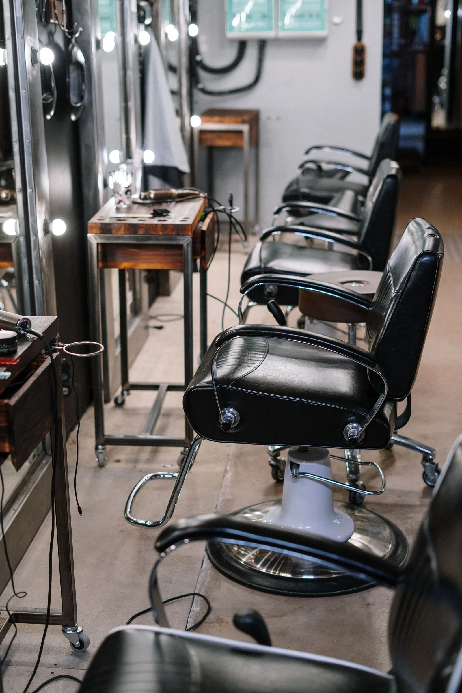 Black leather barber chairs and illuminated mirrors in a barbershop