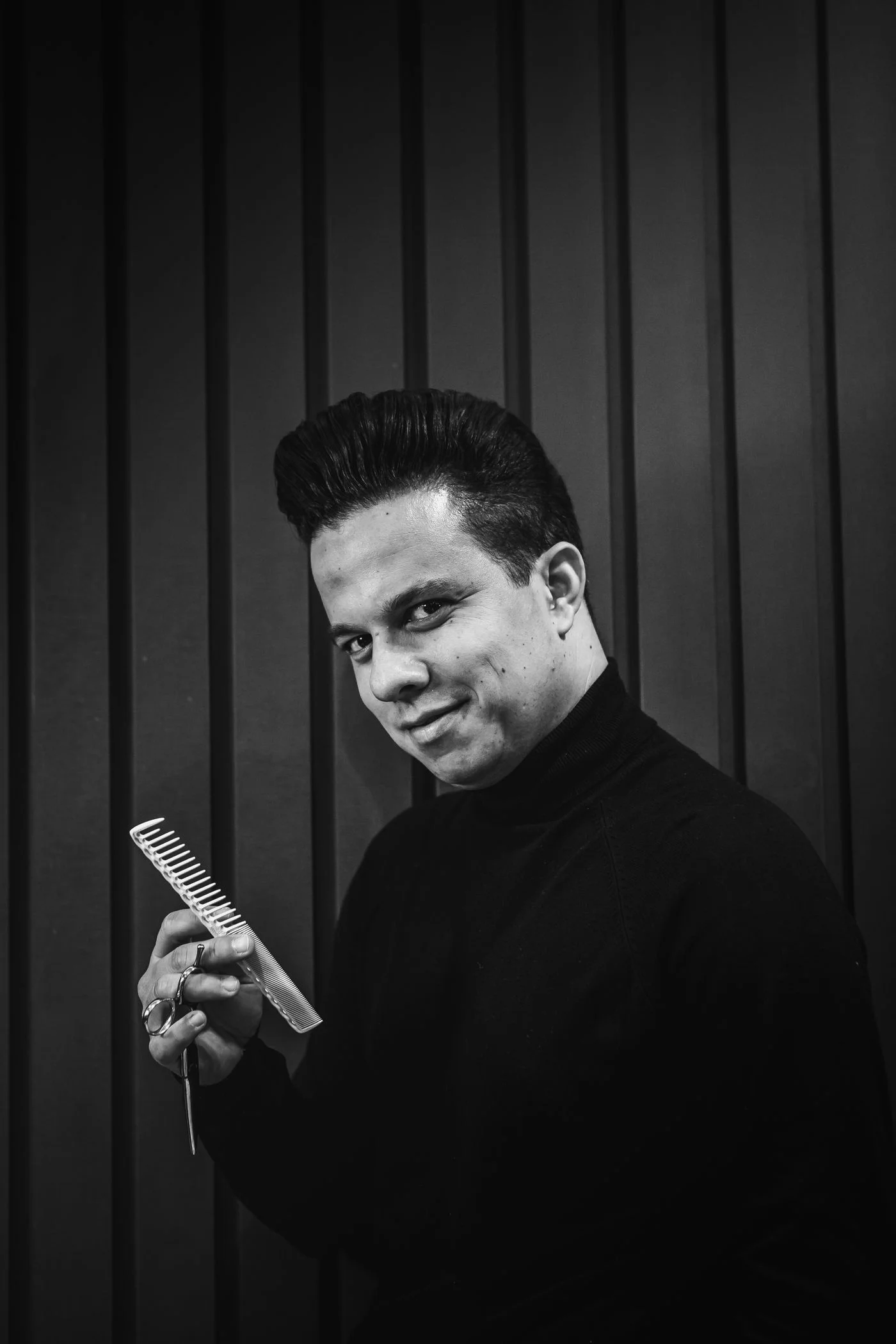 Black-and-white portrait of a barber holding a comb and scissors